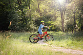 a boy in a helmet rides an orange bicycle. Summer, sun, park.