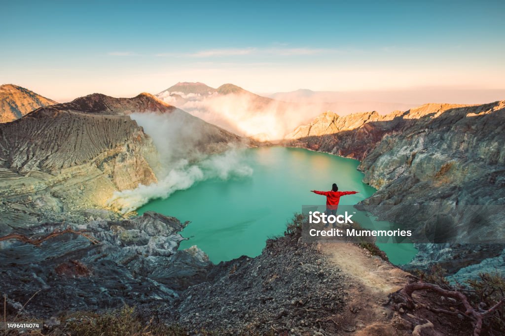 Traveler man standing on the crater of Kawah Ijen volcano with sunrise sky in the morning Successful traveler man standing on the crater of Kawah Ijen volcano with sunrise sky in the morning at East Java, Indonesia Indonesia Stock Photo