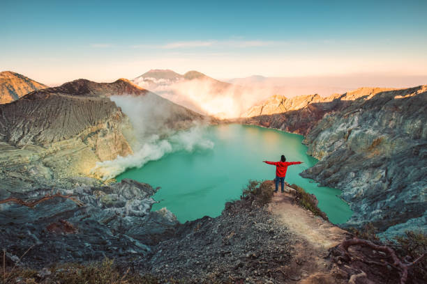 Traveler man standing on the crater of Kawah Ijen volcano with sunrise sky in the morning stock photo