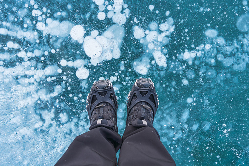 Man in boots standing on frozen lake with natural bubble in winter at Canada
