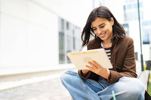 istock Young woman using her digital tablet outdoors 1496422803