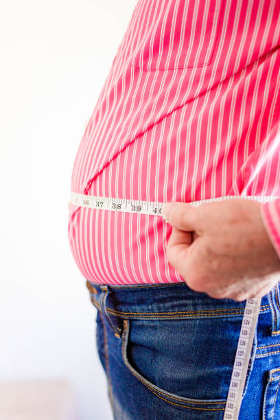 istock Overweight man measuring waist using tape measure 1496423100