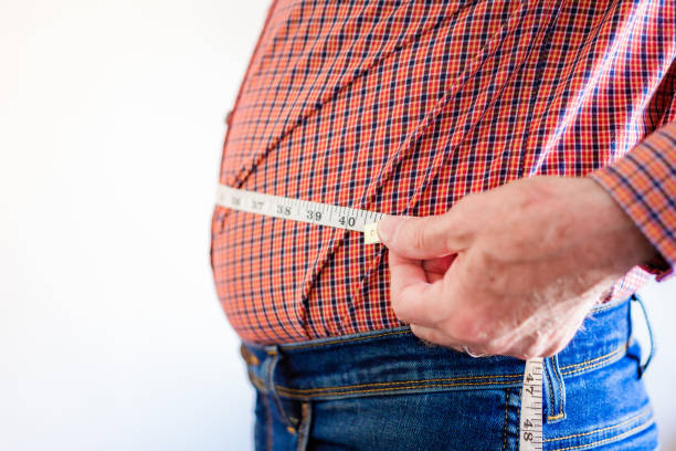 istock Overweight man measuring waist using tape measure 1496423159