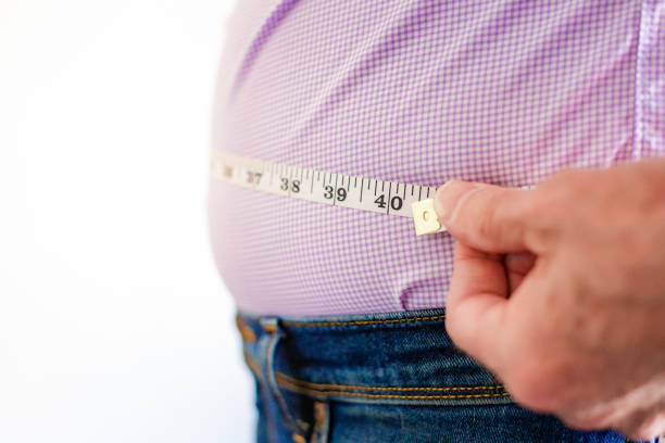 istock Overweight man measuring waist using tape measure 1496423160