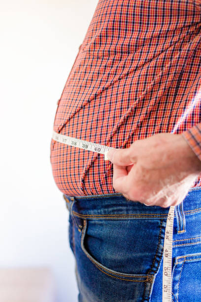 istock Overweight man measuring waist using tape measure 1496423186