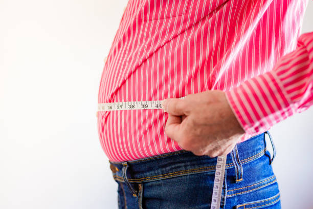 istock Overweight man measuring waist using tape measure 1496423196