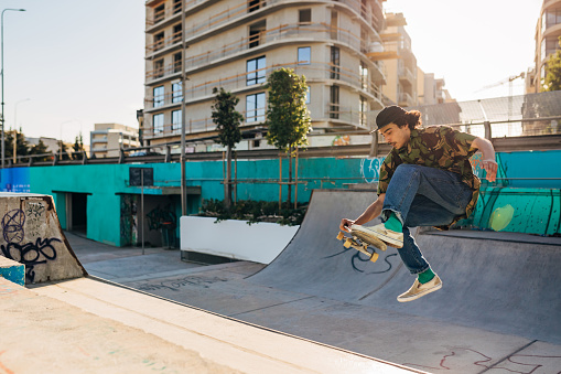 Concentrated male skater performs various jumps and exhibitions with a skate in a skate park