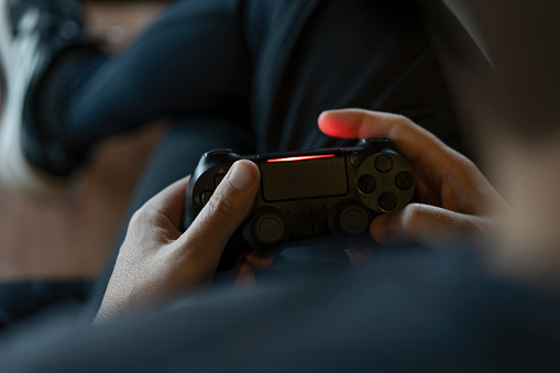Close-up of an adult man's hands holding a joystick while playing a video game on a console.