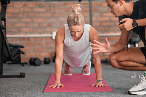 Fitness, push up and people, personal trainer or woman in gym coaching for support, performance check and muscle goals. Athlete, sports person in strong workout, exercise motivation or training timer fitness, push up y personas, entrenador personal o mujer en gimnasio entrenando para apoyo, control de rendimiento y objetivos musculares. atleta, deportista en entrenamiento fuerte, motivación de ejercicio o temporizador de entrenamiento