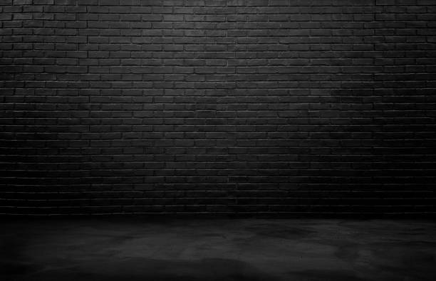istock industrial background for product displayed. black brick wall background, rough concrete, plastered concrete floor, with lights from above. lighting effect on empty brick wall background for design. 1496433274