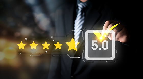 Review, increase rating or ranking, evaluation and classification concept. Businessman draw check Mark on five yellow star to increase rating of his company. Bokeh in background.