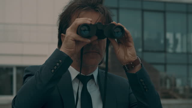 Businessman with binoculars on the background of a glazed building