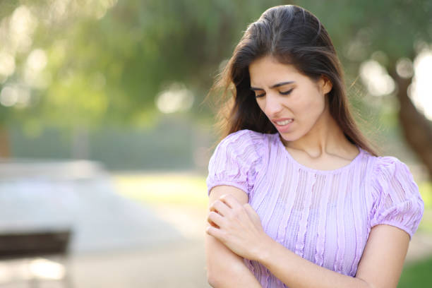 istock Woman scratching arm standing in a park 1496435779