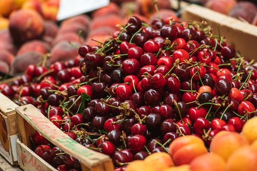 Fresh ripe red cherry or cherries fruit in a wooden box in a farmer agricultural open air market, seasonal healthy food. Concept of biological, bio products, bio ecology