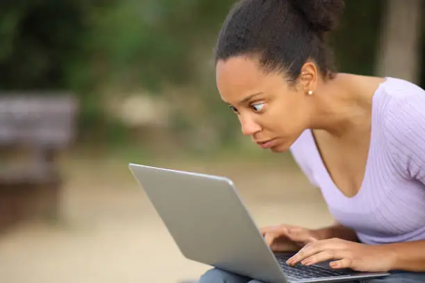 Photo of Shocked black woman checking laptop content