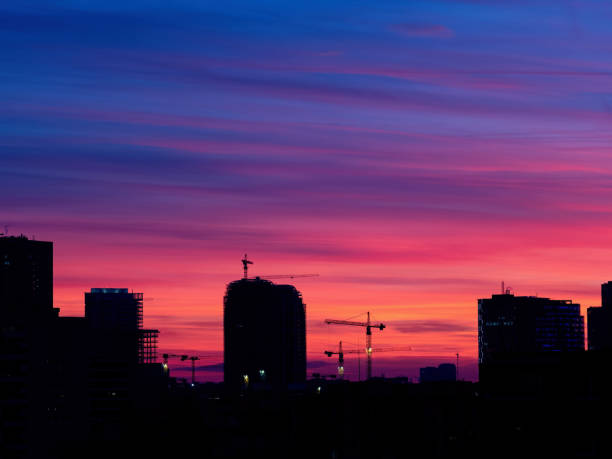 istock Silhouette of a skyscraper under construction and cranes in the evening sky. 1496438871