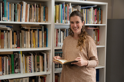 Portrait of a mid adult woman reading a book in the library