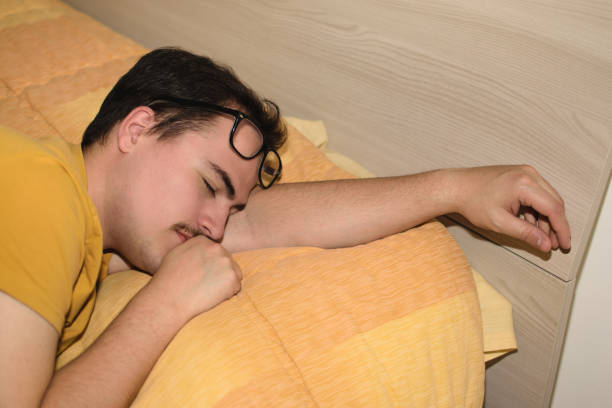 istock Young man with black eyeglasses on his forehead sleeping turned in bed. 1496441276
