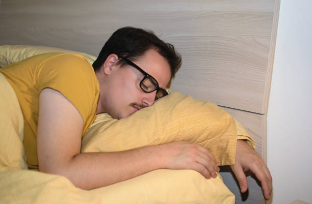 istock Young man with black eyeglasses sleeping turned in bed. 1496441287
