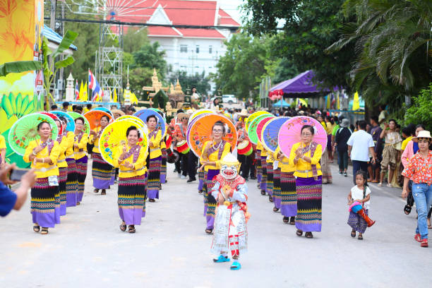 Rum thai dancing  rows  of mature thai dancer women at Public local traditional culture event organized by local government near historical grounds of Wat Wihan Thong Historical Site near Nan river and is local way of keeping history and traditions alive. Women are walking and dancing in rows along street with paper umbrellas