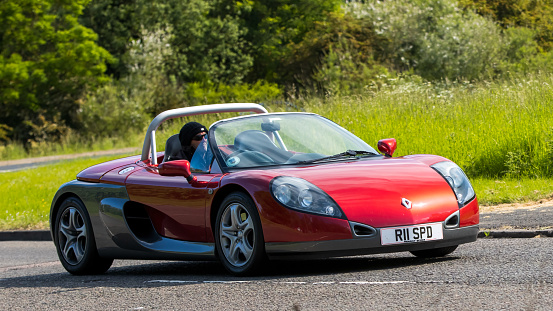 Stony Stratford,UK - June 4th 2023: 1997 red RENAULT SPORT SPIDER    classic car travelling on an English country road.