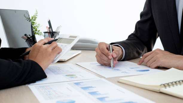 istock Two business people sitting at workplace and discussing about earnings on a graph to plan investments. 1496443867