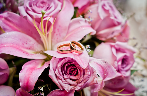 Image of wedding rings over pink lily