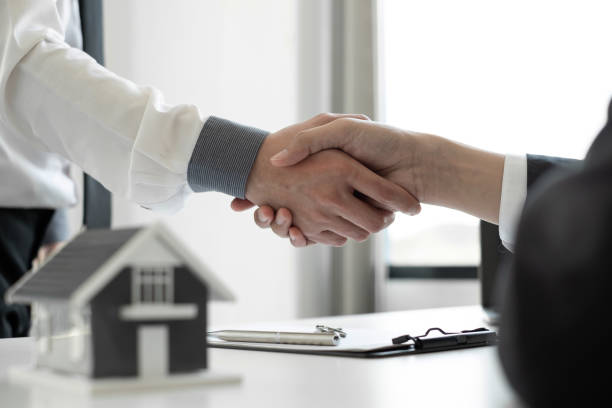 istock Home insurance agent shaking hand with the customer in the office. 1496446966