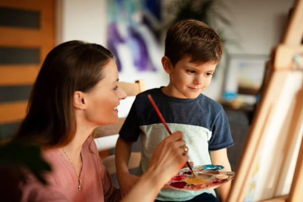 istock Little boy drawing with mom in living room. 1496447901