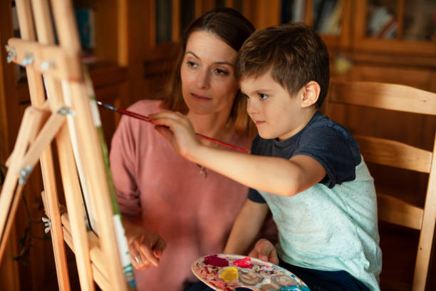 istock Little boy drawing with mom in living room. 1496447903