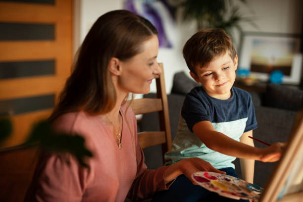 istock Little boy drawing with mom in living room. 1496447904