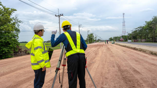 istock Asian engineer holding tablet to inspect work, as foreman uses telescope, telescope and radio to control road construction, against backdrop of road under construction 1496447973