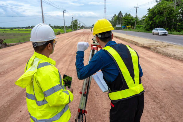 istock Asian engineer holding tablet to inspect work, as foreman uses telescope, telescope and radio to control road construction, against backdrop of road under construction 1496447979