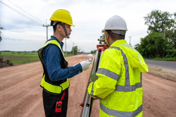 istock Asian engineer holding tablet to inspect work, with foreman using telescope to check pin against road plan, telescope and radio to control road construction, against road background under construction 1496447995