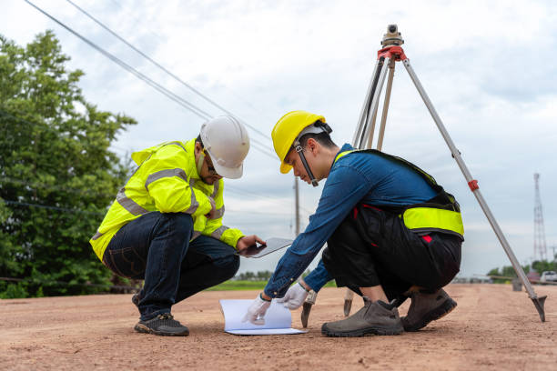 istock Asian engineer holding tablet to inspect work, with foreman using telescope to check pin against road plan, telescope and radio to control road construction, against road background under construction 1496447996