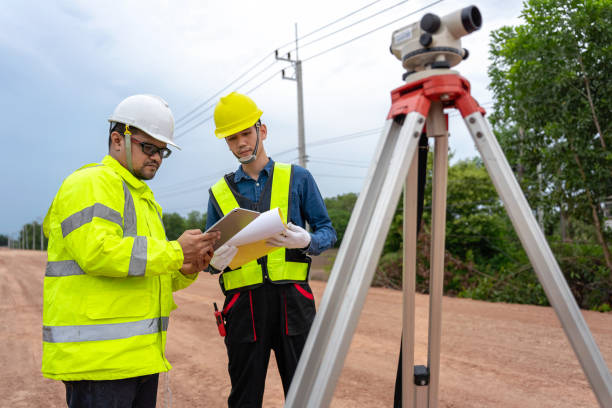 istock Asian engineer holding tablet to inspect work, as foreman uses telescope, telescope and radio to control road construction, against backdrop of road under construction 1496448002