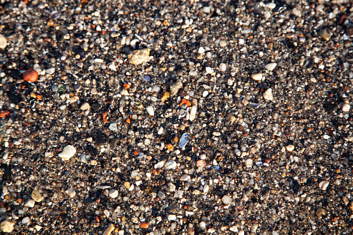 Closeup shot of sand and seastones by the seaside of the beach.
