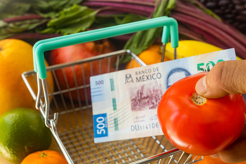 Mexico food, vegetable and fruit prices, Financial concept, Tomato placed in a basket along with a 500 pesos bill