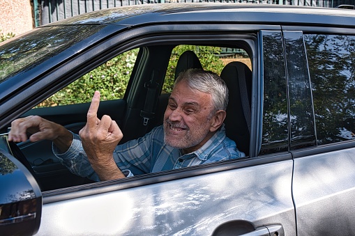 Rudeness in the way. An elderly man shows the middle finger, an obscene gesture.