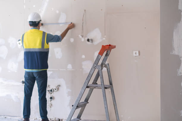 istock Professional architect in protective hardhat measuring wall standing near ladder 1496455203