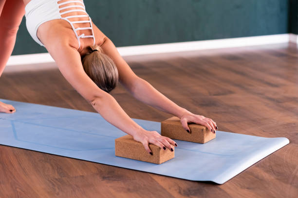 istock Professional yoga exercise flexible woman putting hands on special blocks 1496459741