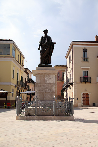 Venosa, Province of Potenza, Italy - 3 june 2023: Statue of Orazio Flacco, Latin poet - Made in honor of the poet who was born in Venosa, the monument is the protagonist of the nineteenth-century urban arrangement of the square on which the Palazzo della Magistrates was also built. Of simple and essential lines, the work does not go beyond its historical-commemorative purposes.