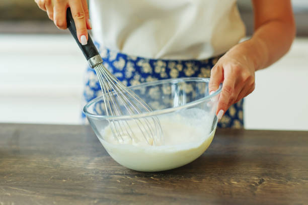 istock Beautiful hands stir the dough with a black whisk in a deep transparent bowl. 1496463517