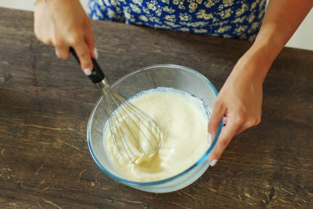 istock Beautiful hands stir the dough with a black whisk in a deep transparent bowl. 1496463523
