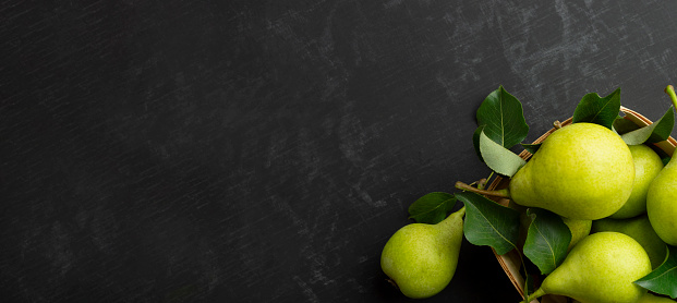 Fresh bio pears with leaves.Fresh pears in the tray. On wooden background. Fresh ripe pears.Space for text. Top view, flat lay. Copyspace. Banner.