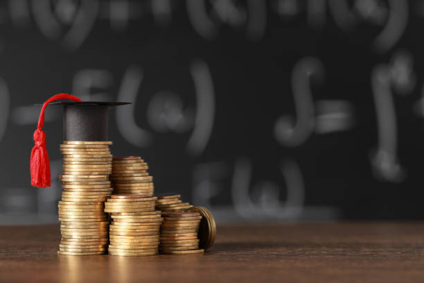 istock Scholarship concept. Coins and graduation cap on wooden table, space for text 1496466238