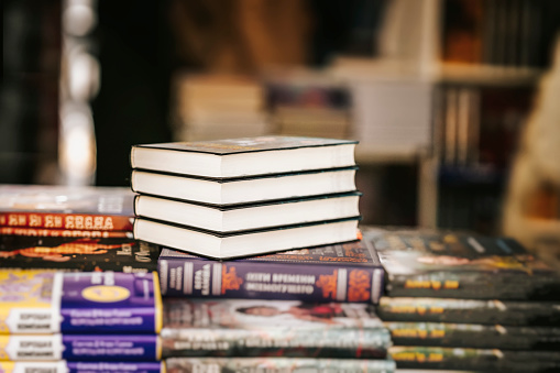 Closeup of books stack on table in book store, selective focus. Education, school, study, reading fiction concept