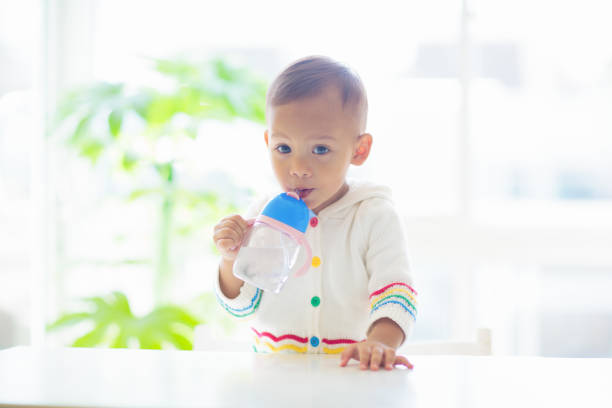 Baby Drinking from a Pink Sippy Cup in a Cozy Kitchen