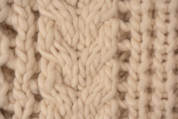 istock A fragment of beige knitted fabric, knitted from white sheep wool. 1496466733
