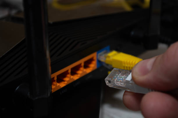 istock Close-up of a man's hand, fingers connecting a network cable to a router. 1496468452
